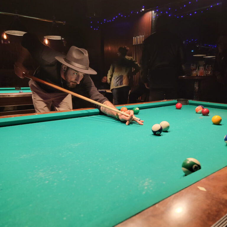 A customers in a cool hat shoots pool at Banter Bar West Los Angeles