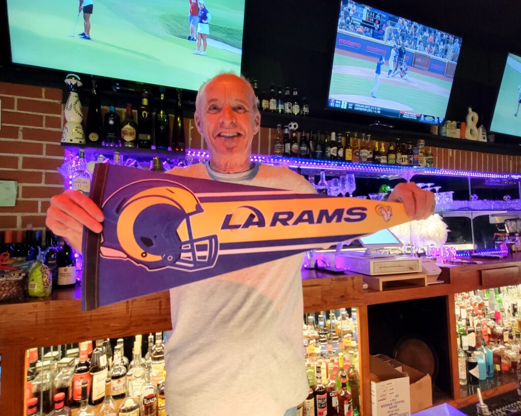 Banter Bar bartender Barney hold a Los Angeles Rams banner for the camera.