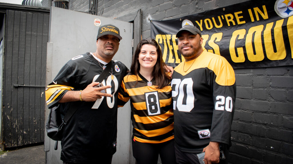 Steelers fans post for a picture in the back parking lot of Banter Bar